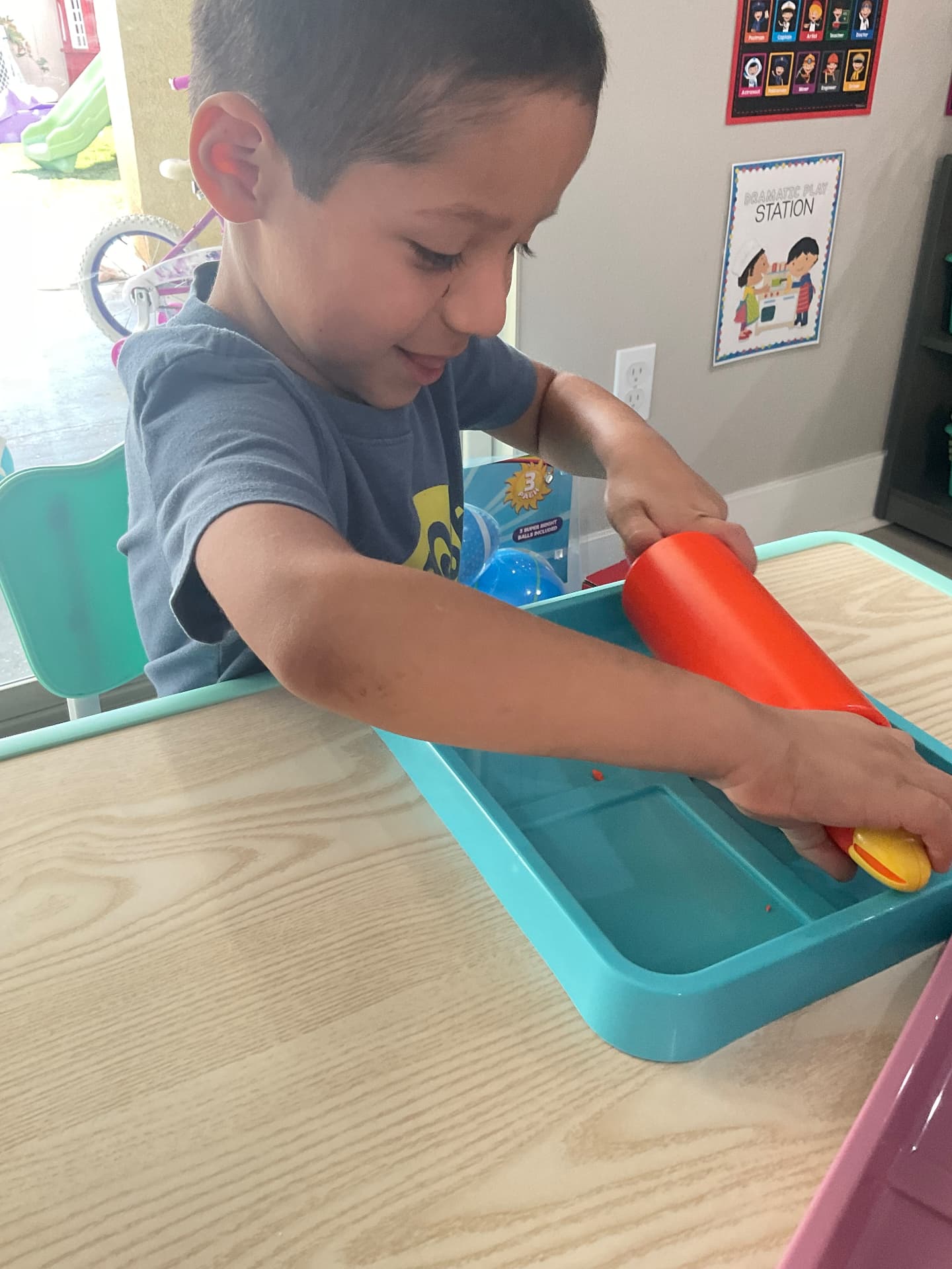 Preschooler exploring a sensory tray at the play table
