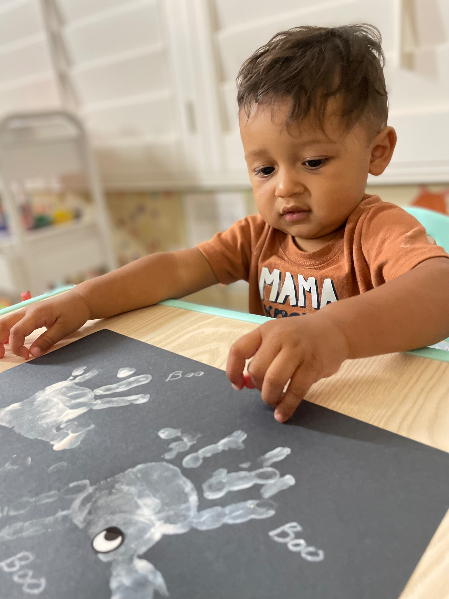 Toddler making white handprint ghosts on black paper