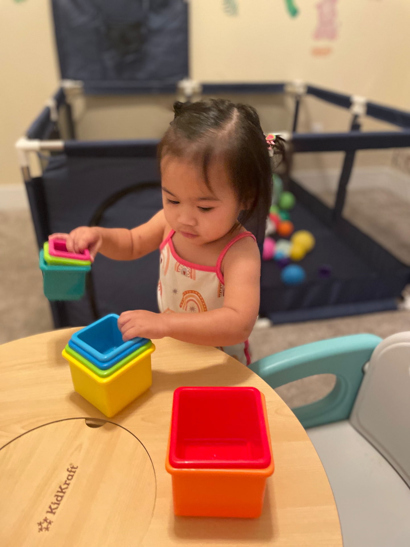 Toddler nesting colorful stacking cups at the play table