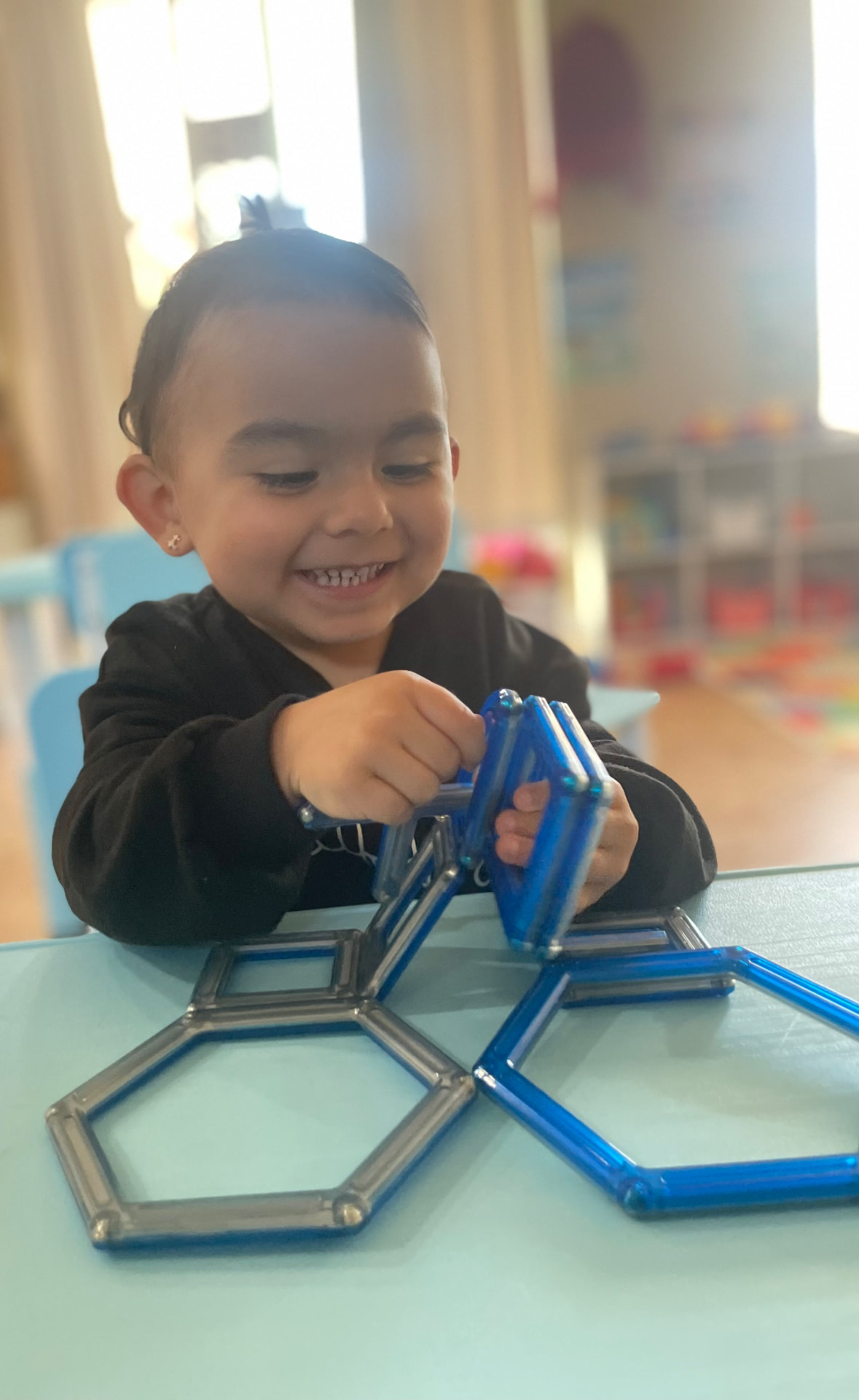 Child building hexagons with magnetic tiles at a learning table