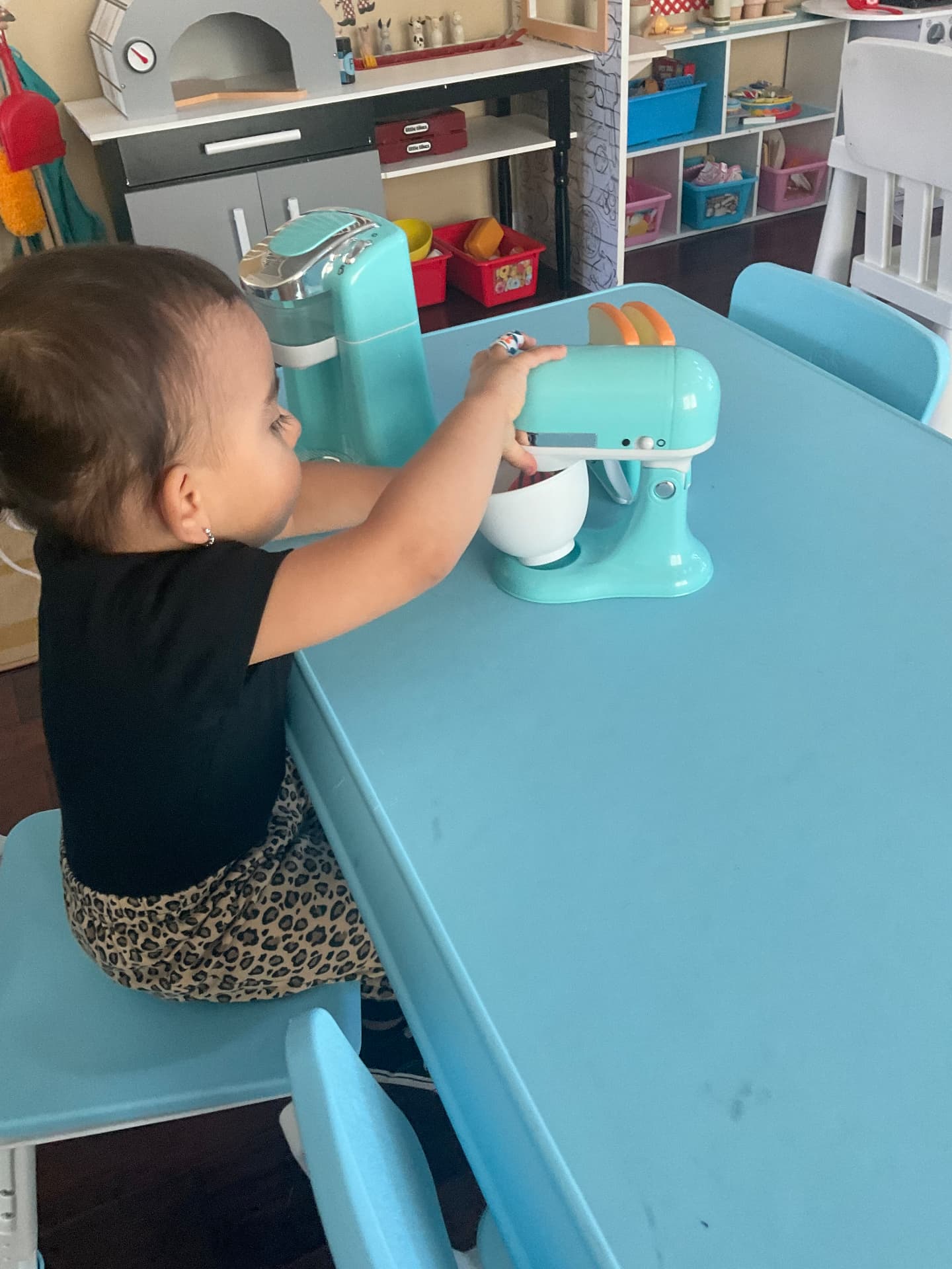 Child using a toy stand mixer in the play kitchen area