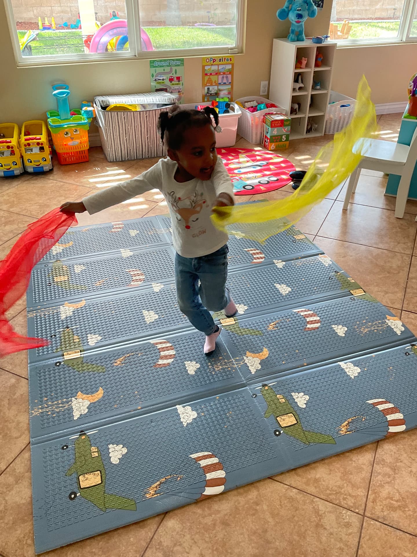 Child dancing with red and yellow scarves on a play mat