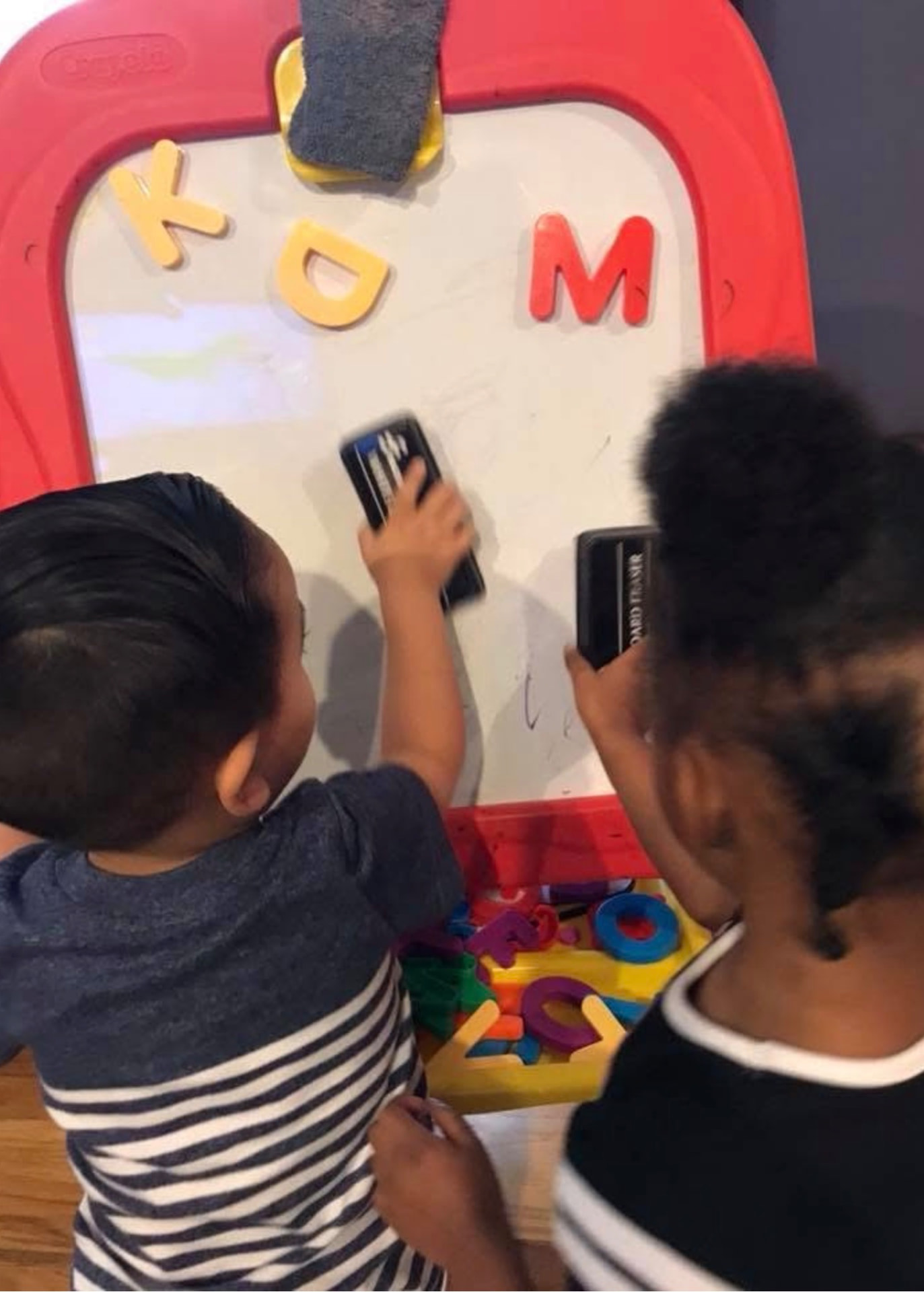 Two children working with magnetic letters on an easel