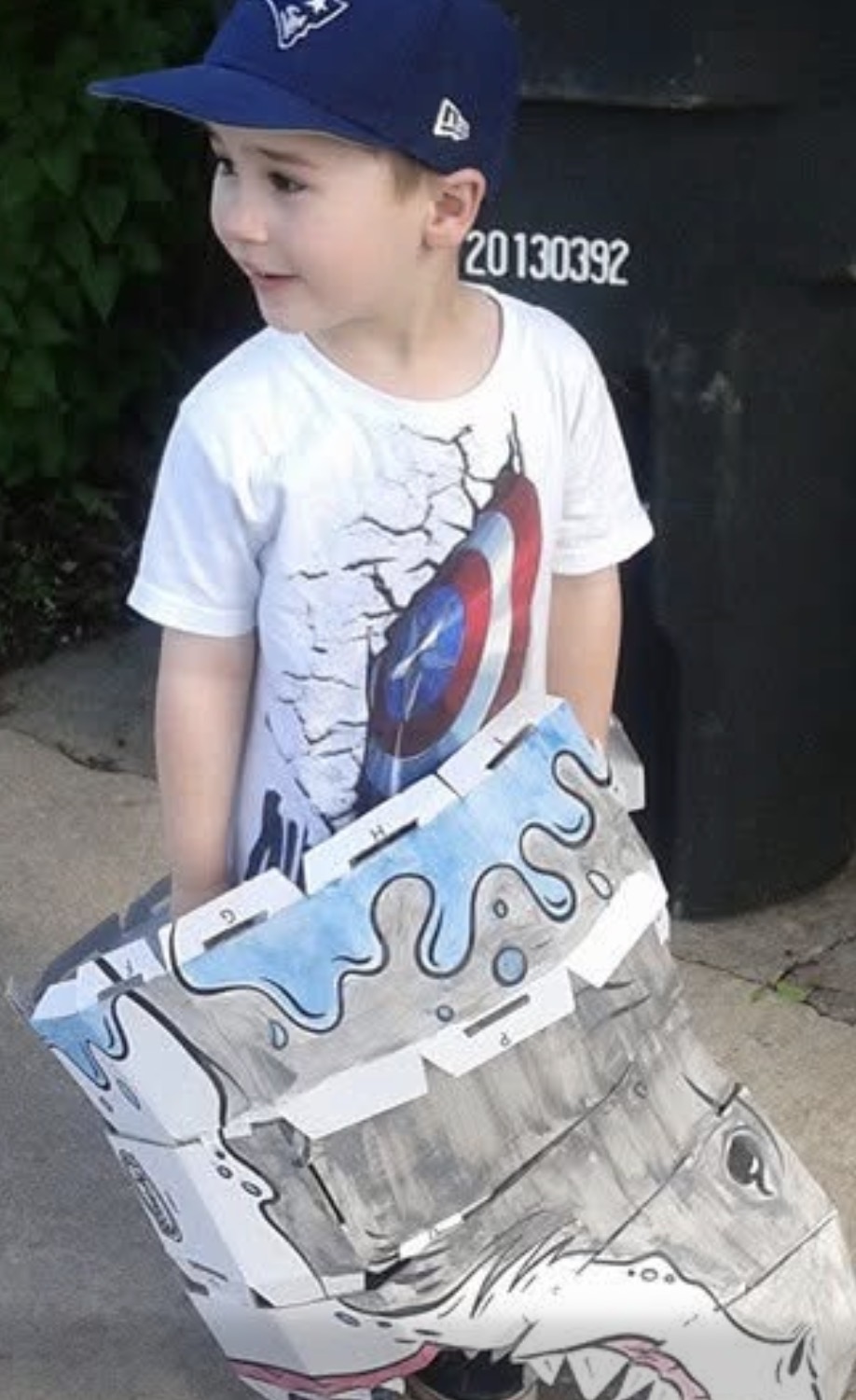 Child wearing a handmade cardboard shark costume outside
