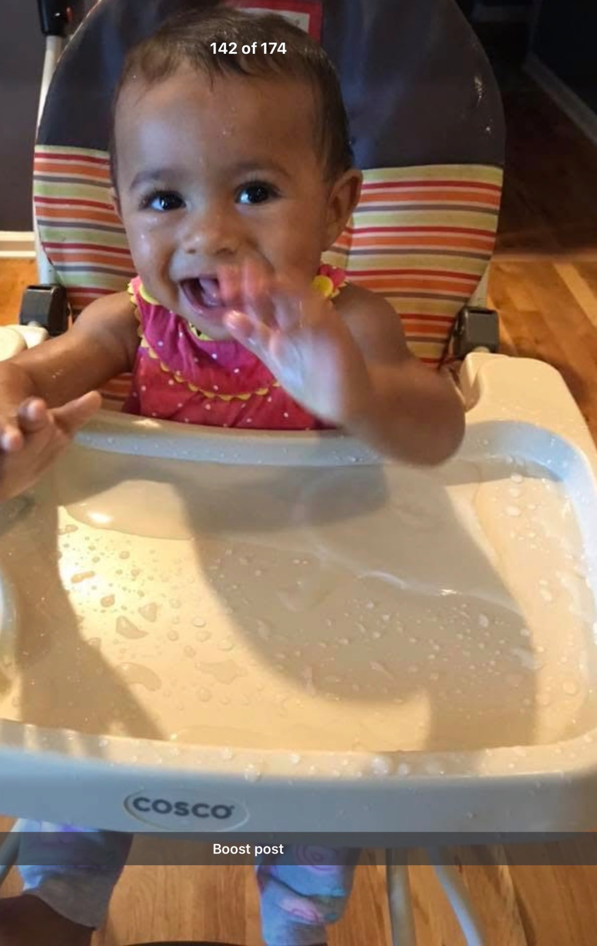 Smiling baby waving from a high chair