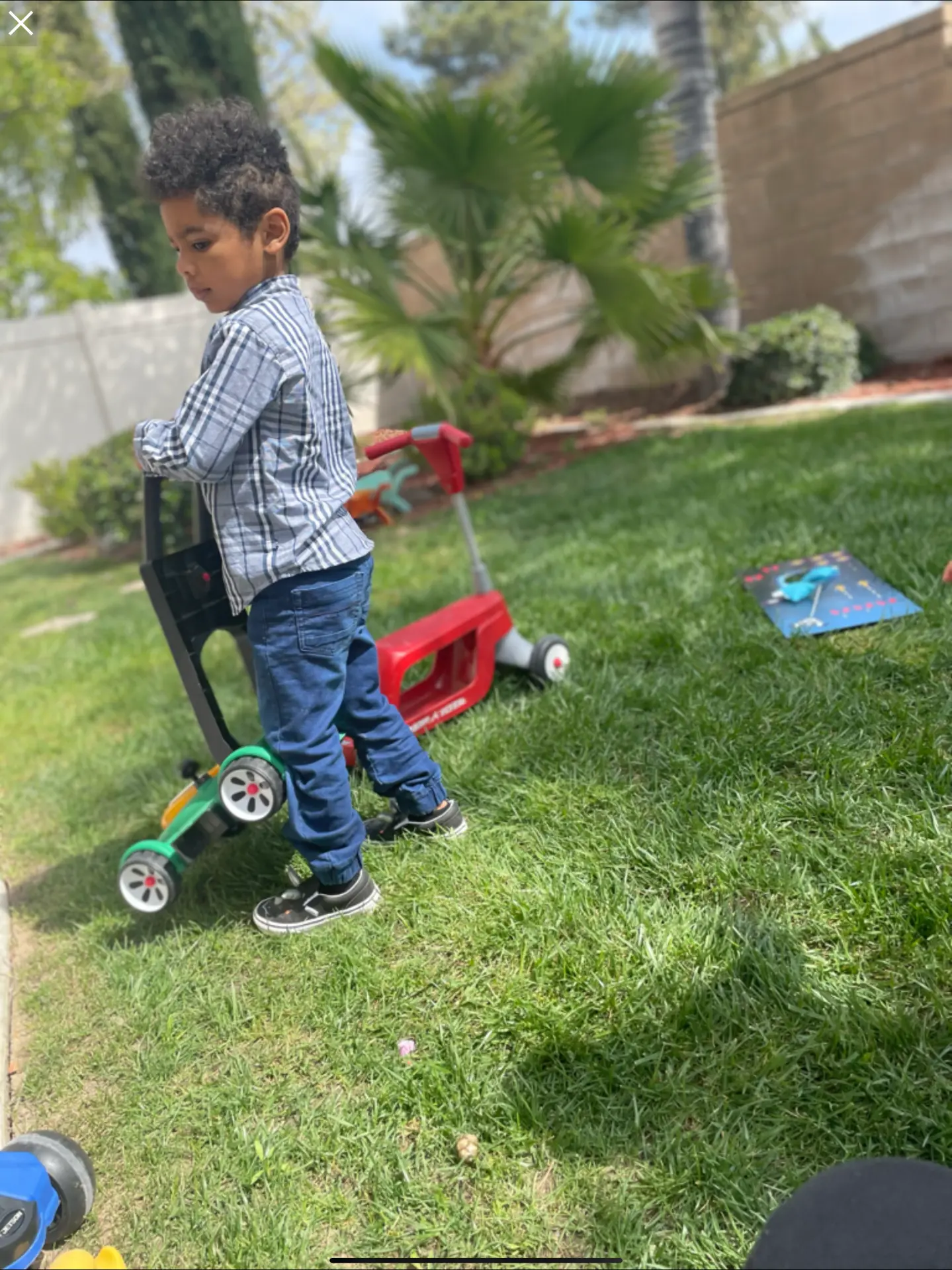 Child pushing a ride-on toy across the grassy yard