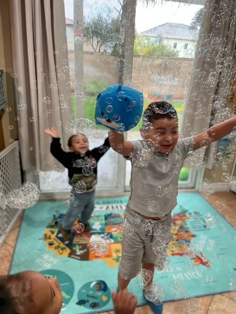 Children jumping and laughing among bubbles on a world map rug