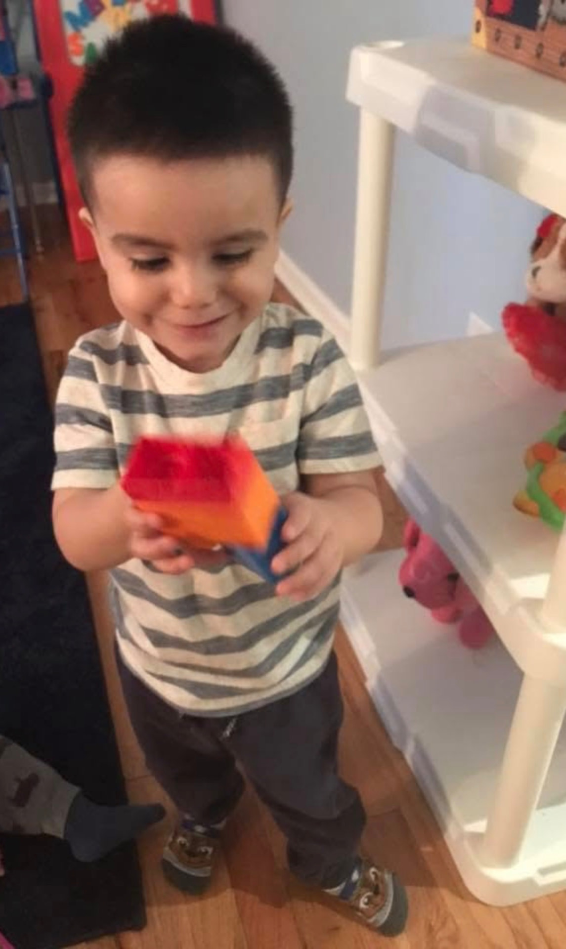 Toddler smiling while exploring a colorful foam block