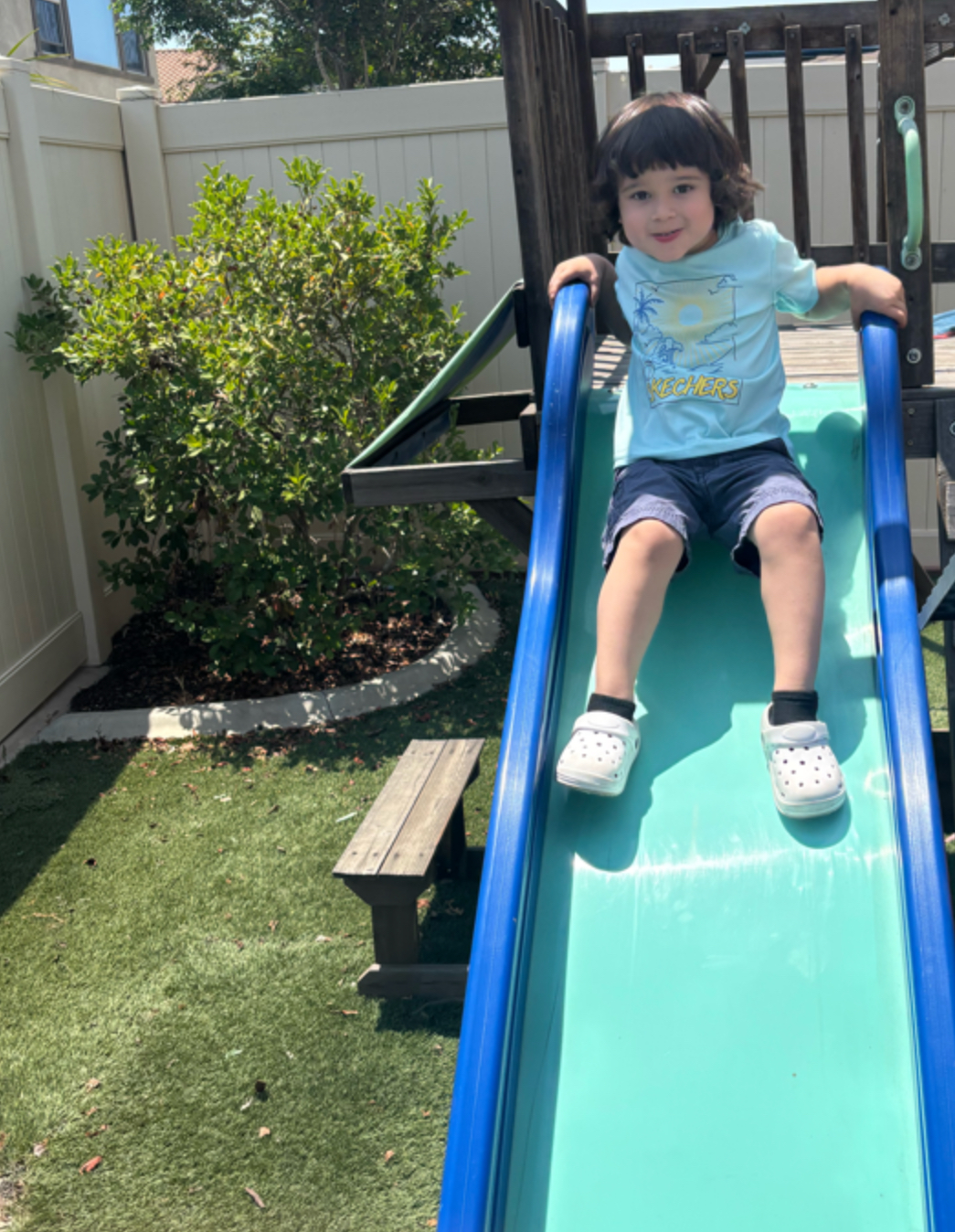 Child sliding down the big backyard playset slide