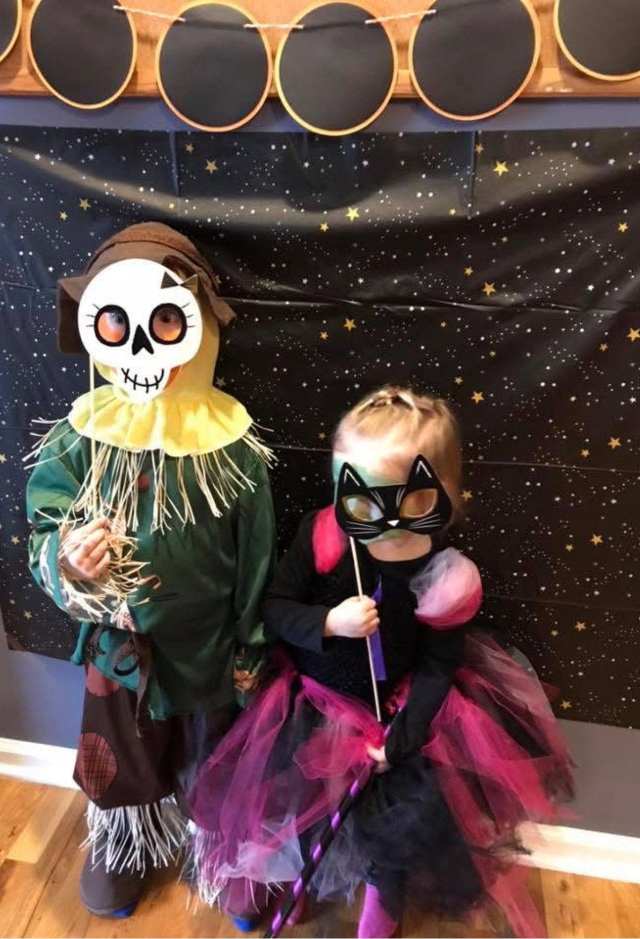 Two children in costumes posing at a starry photo backdrop