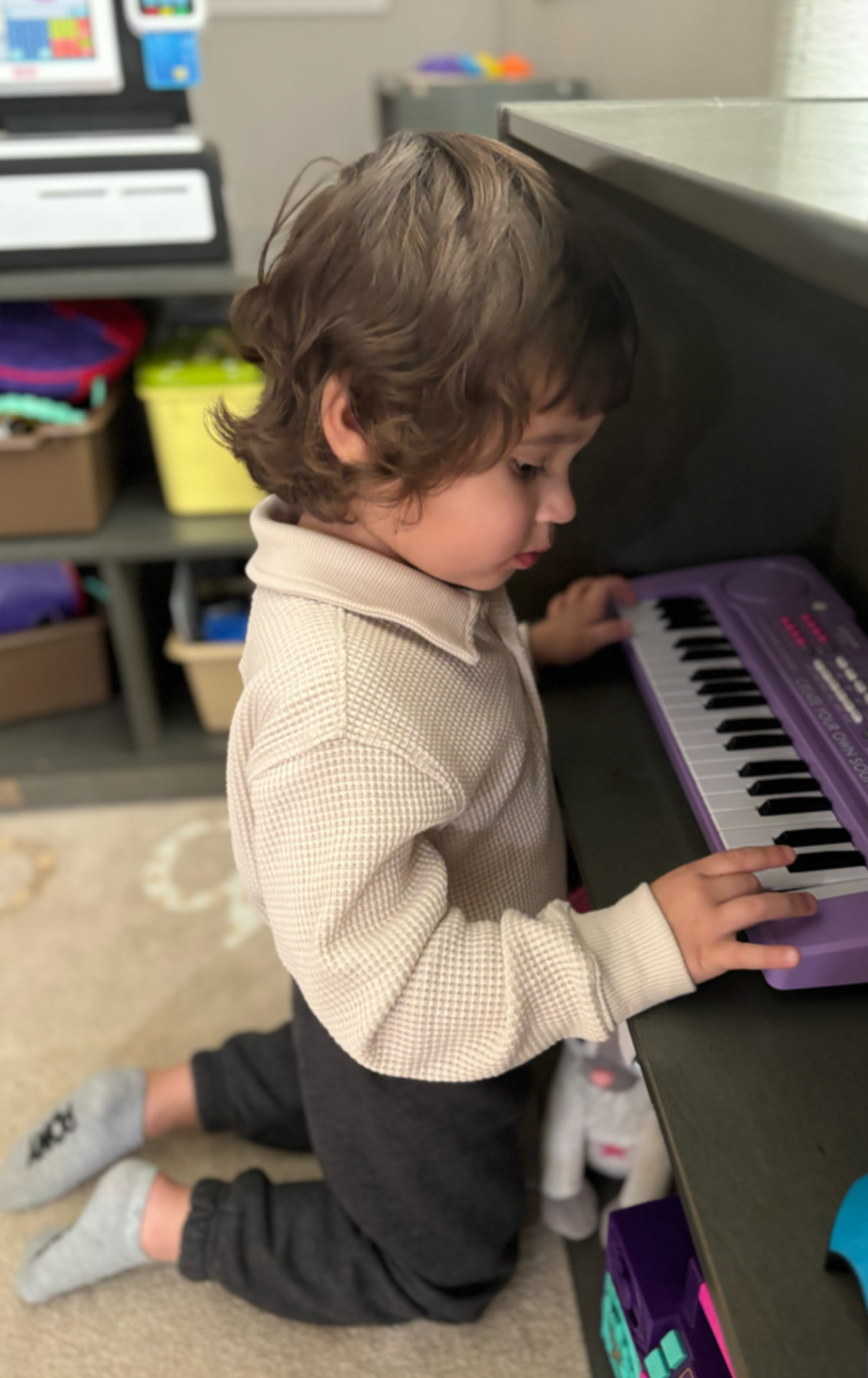 Toddler pressing keys on a purple toy keyboard