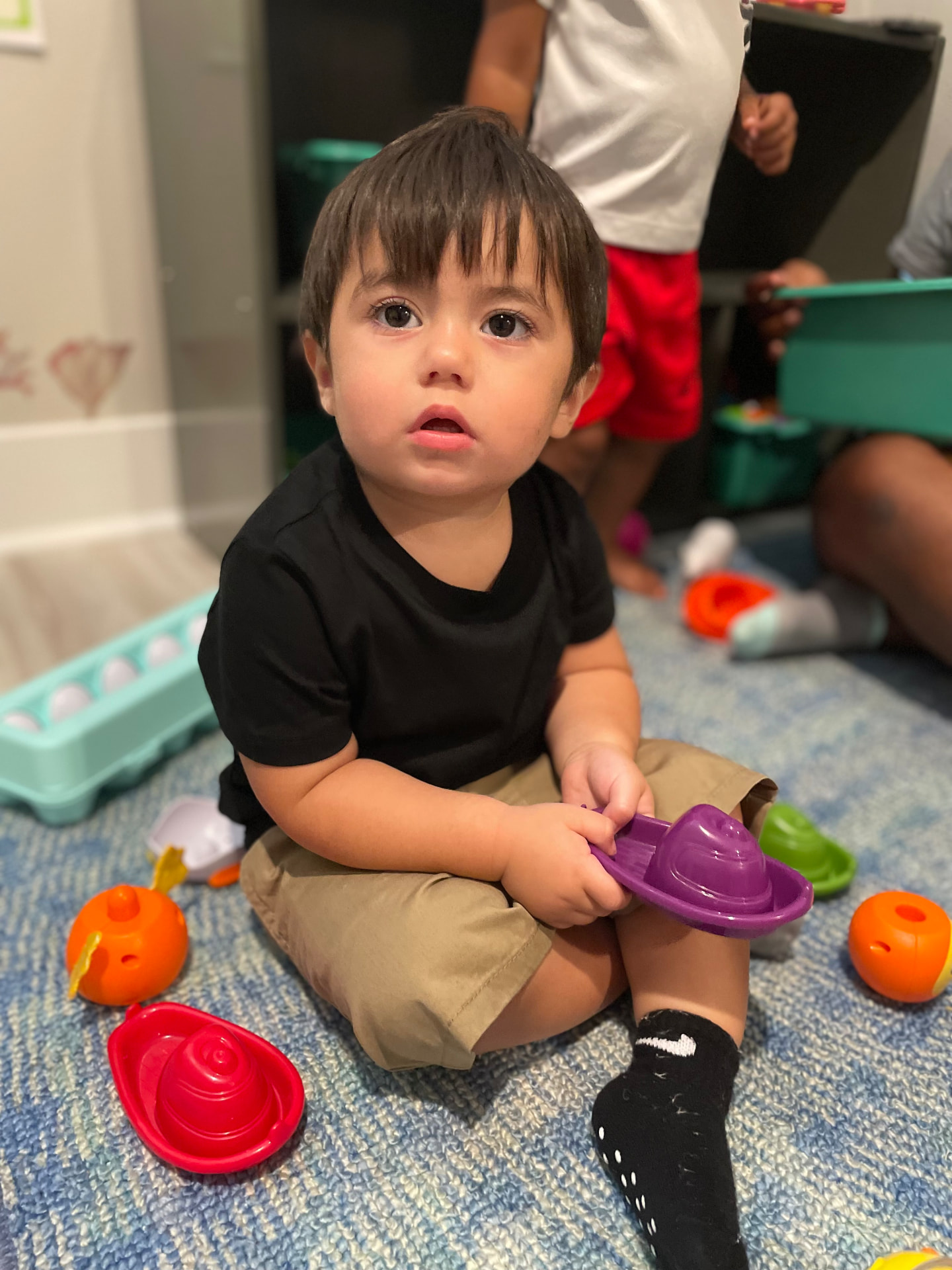 Toddler matching colorful egg shape toys on the rug