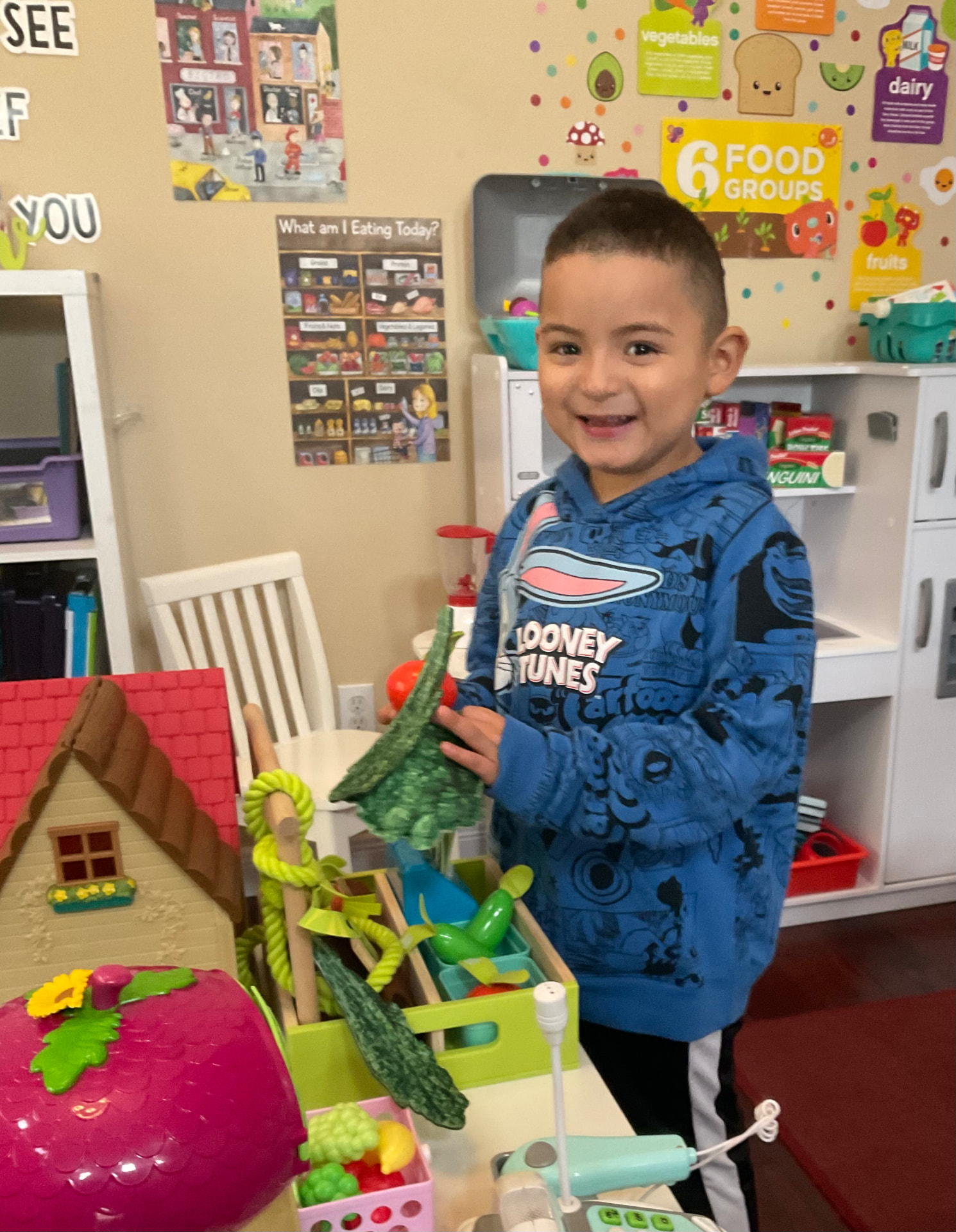 Smiling child holding pretend vegetables at the play market