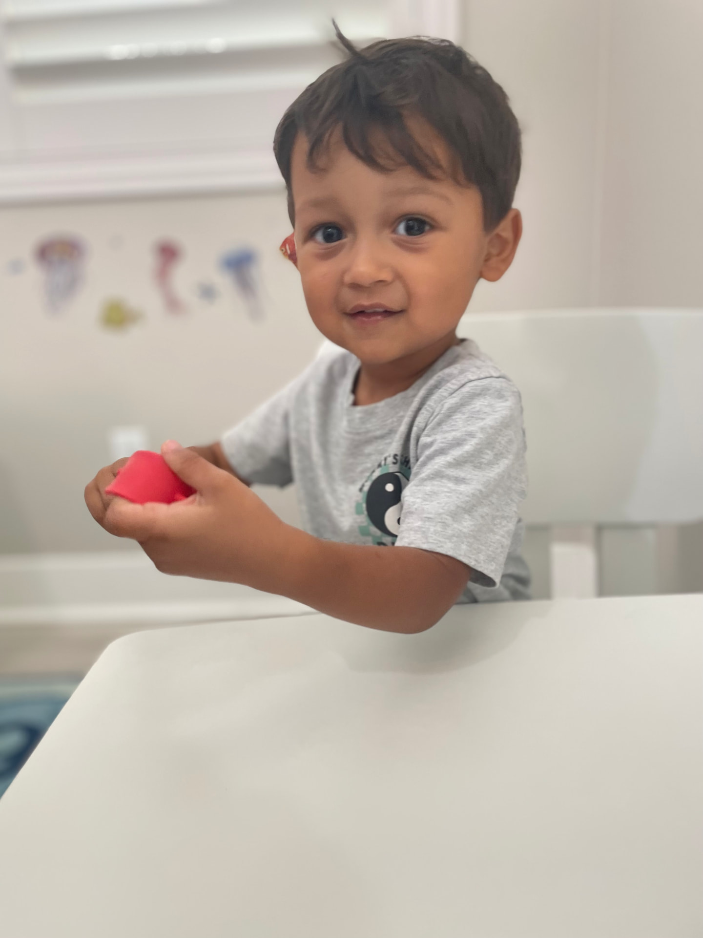 Preschooler at the table shaping red play dough