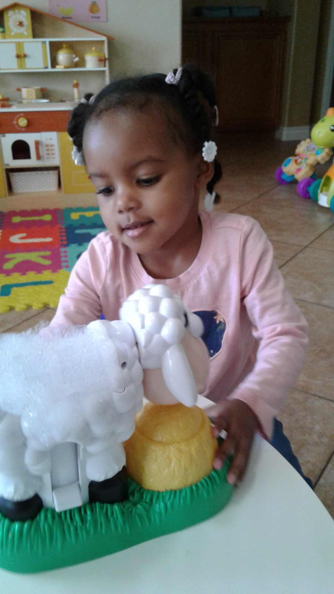 Toddler playing with a lamb figure on a farm toy at the table