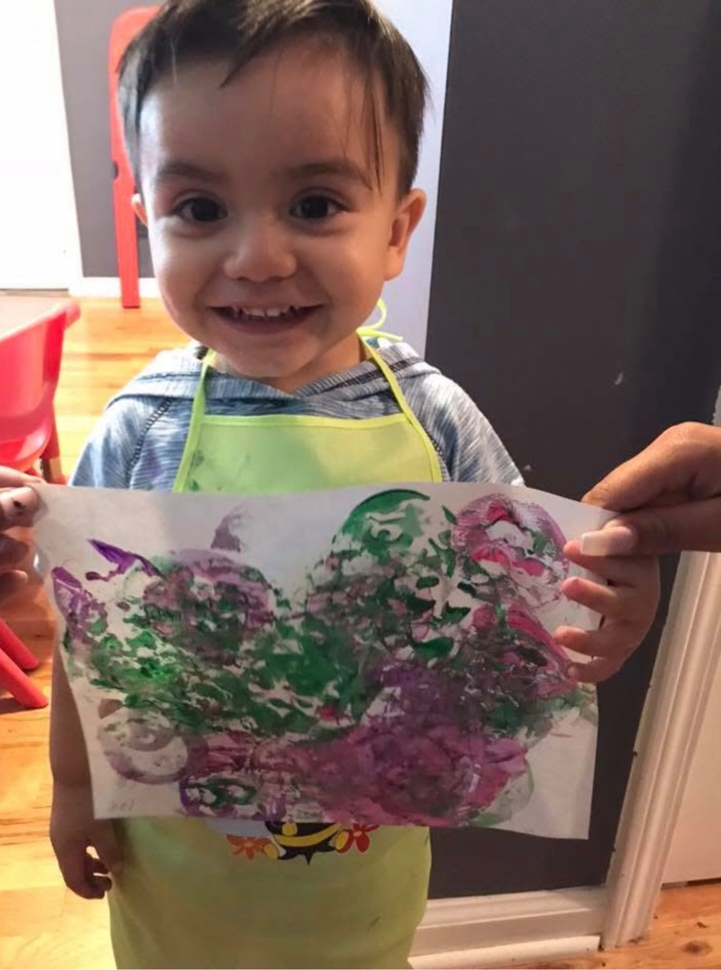 Smiling toddler holding up a colorful paint print artwork
