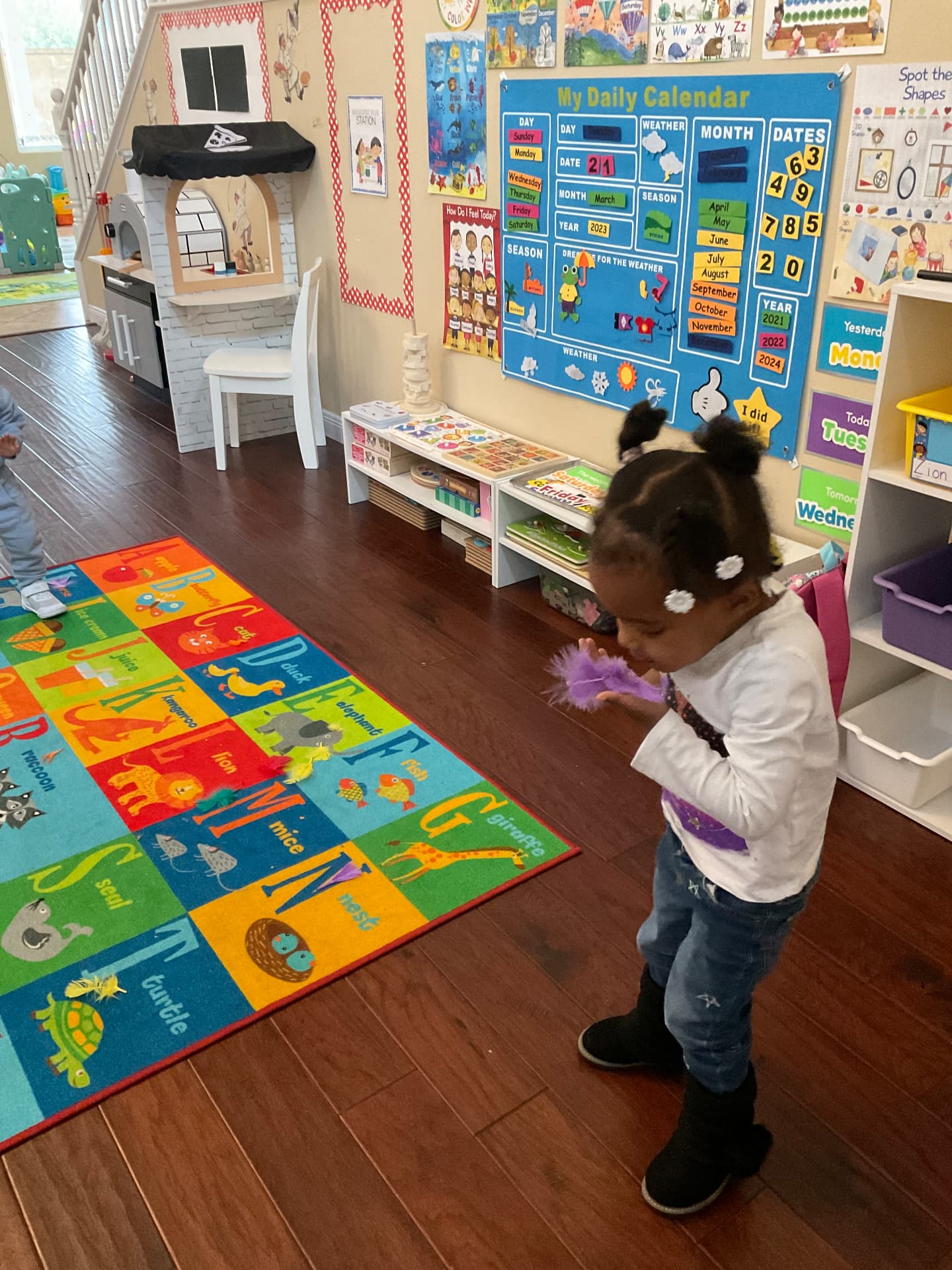 Child by the daily calendar board holding a purple feather