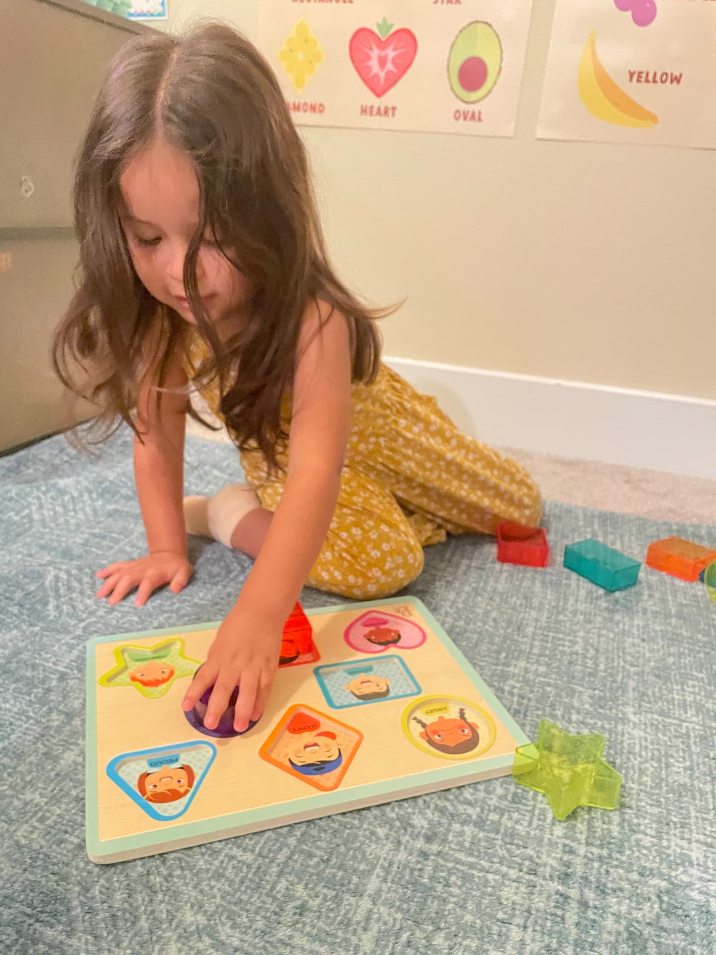 Child fitting pieces into a wooden shape puzzle on the rug