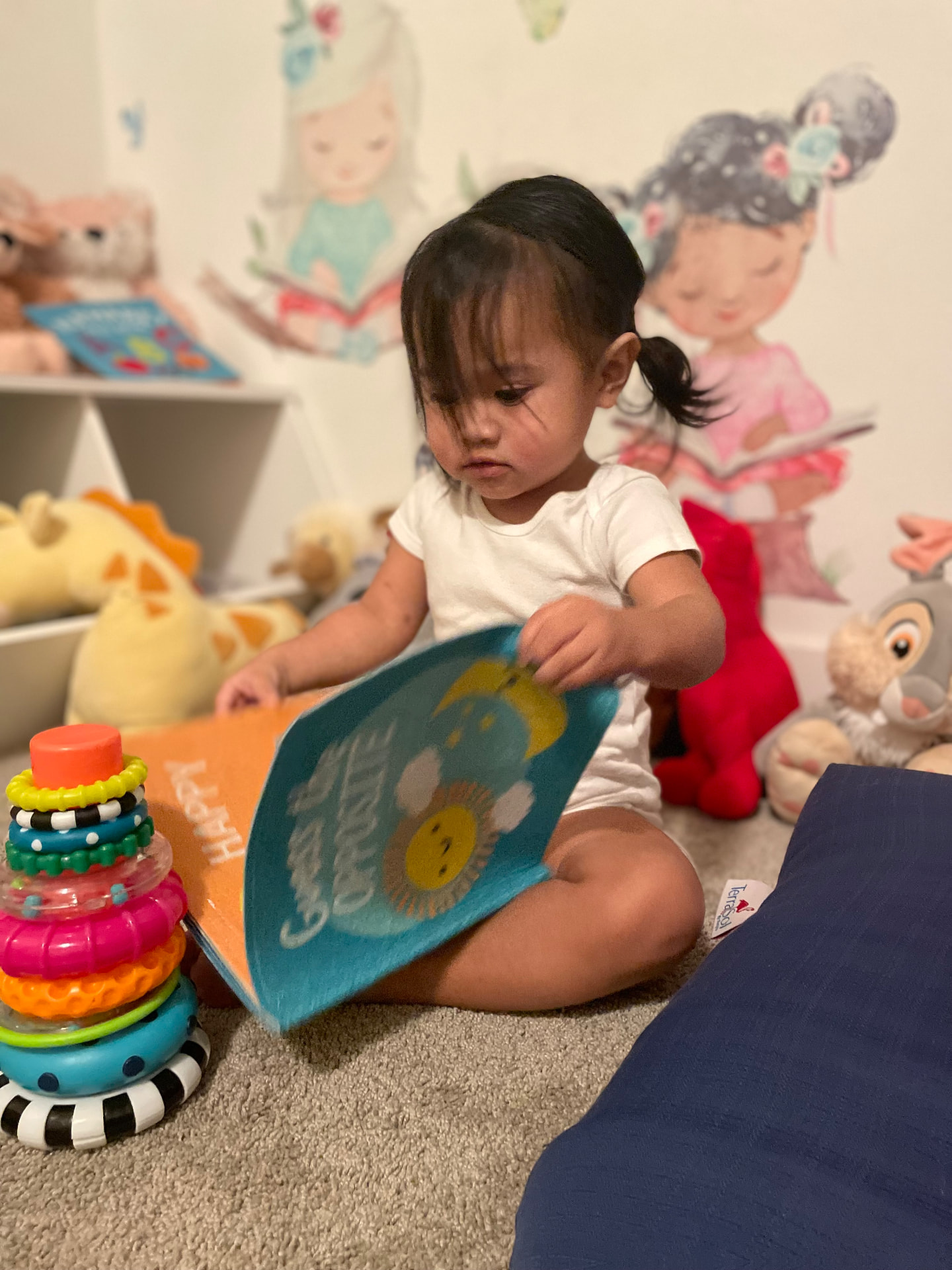 Toddler turning the pages of a board book in the cozy corner