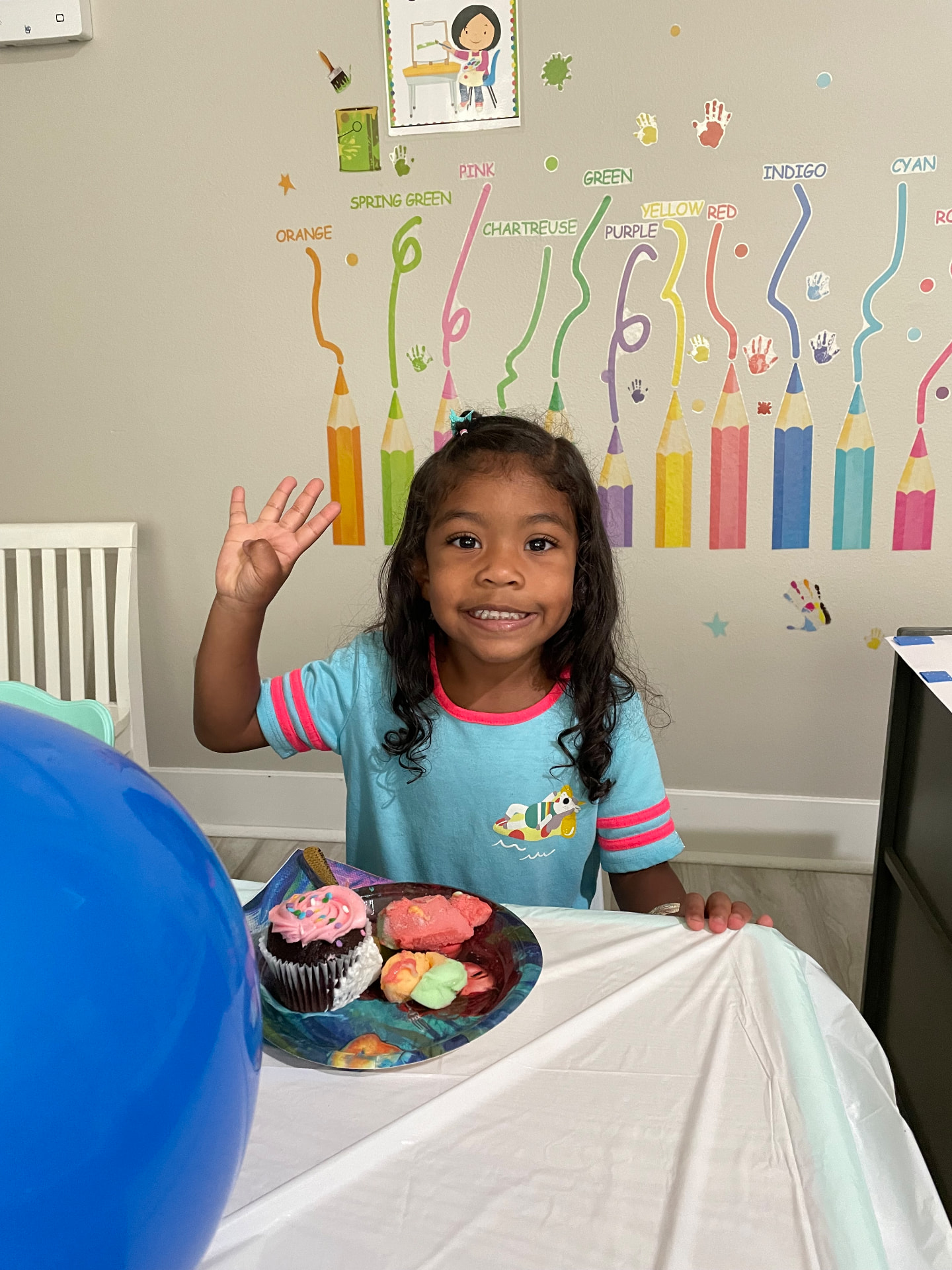 Preschooler waving with a treat plate at a classroom celebration