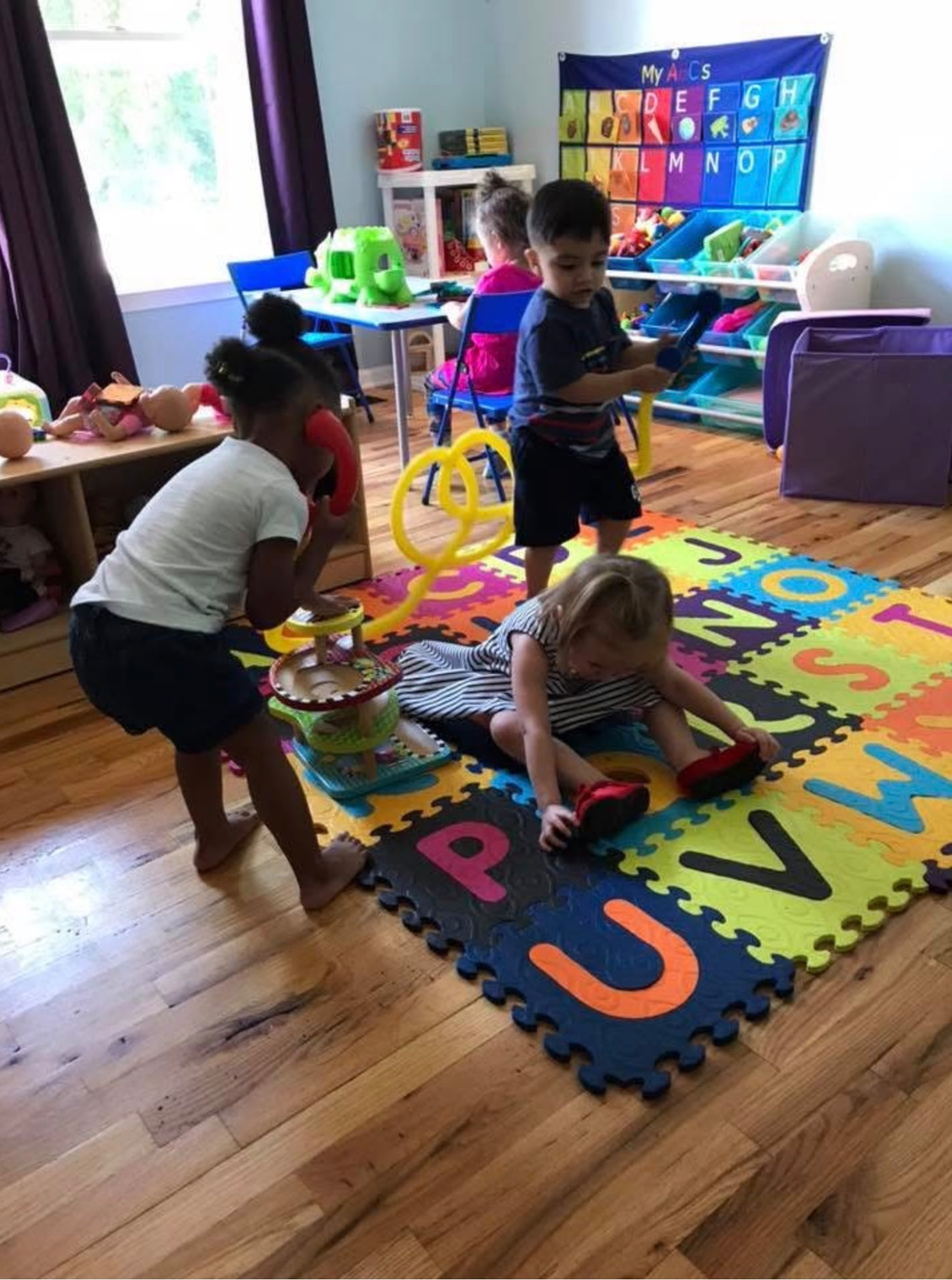 Children playing together on a colorful alphabet foam mat