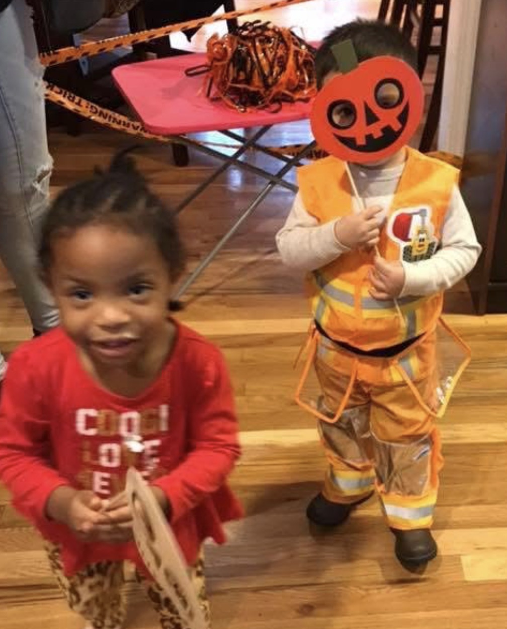 Two children in costumes with a pumpkin mask at a fall party