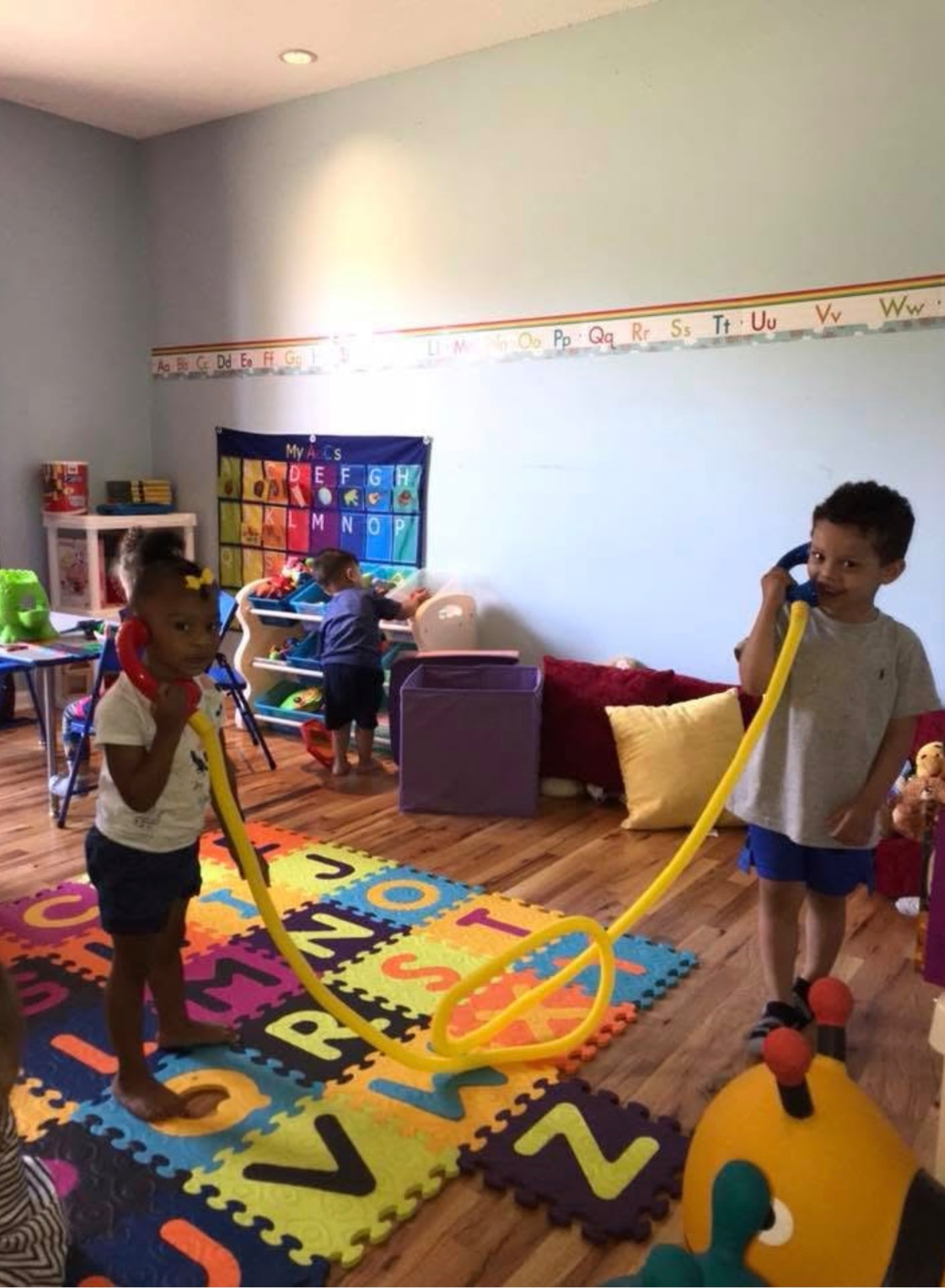 Two children talking on toy telephones in the playroom