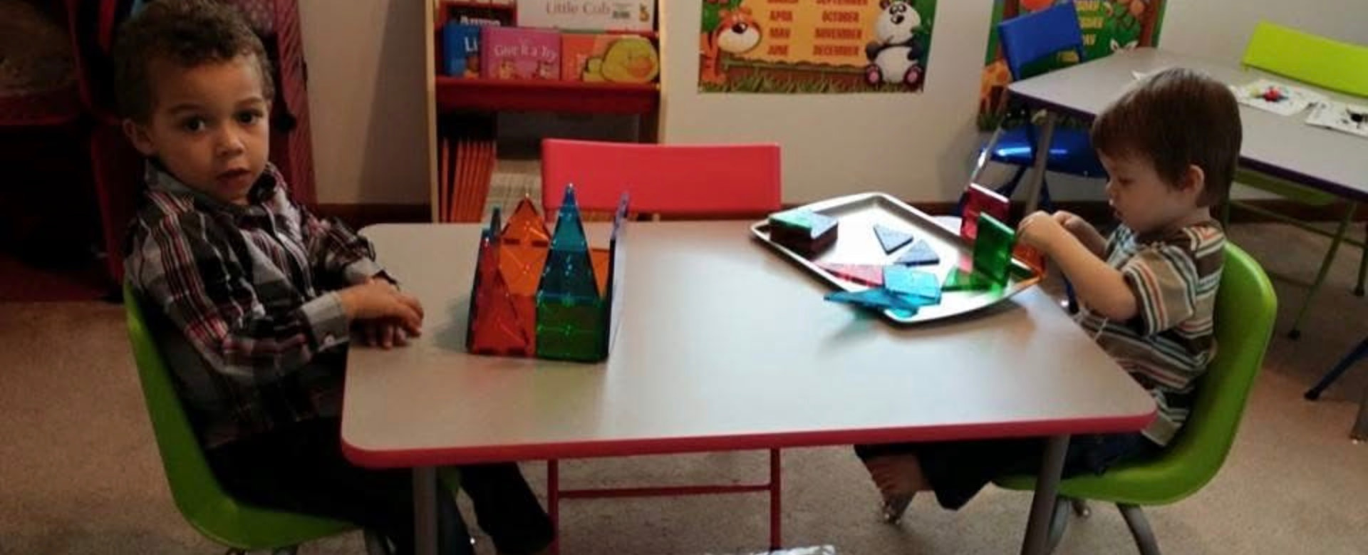 Two children building with magnetic tiles at a table