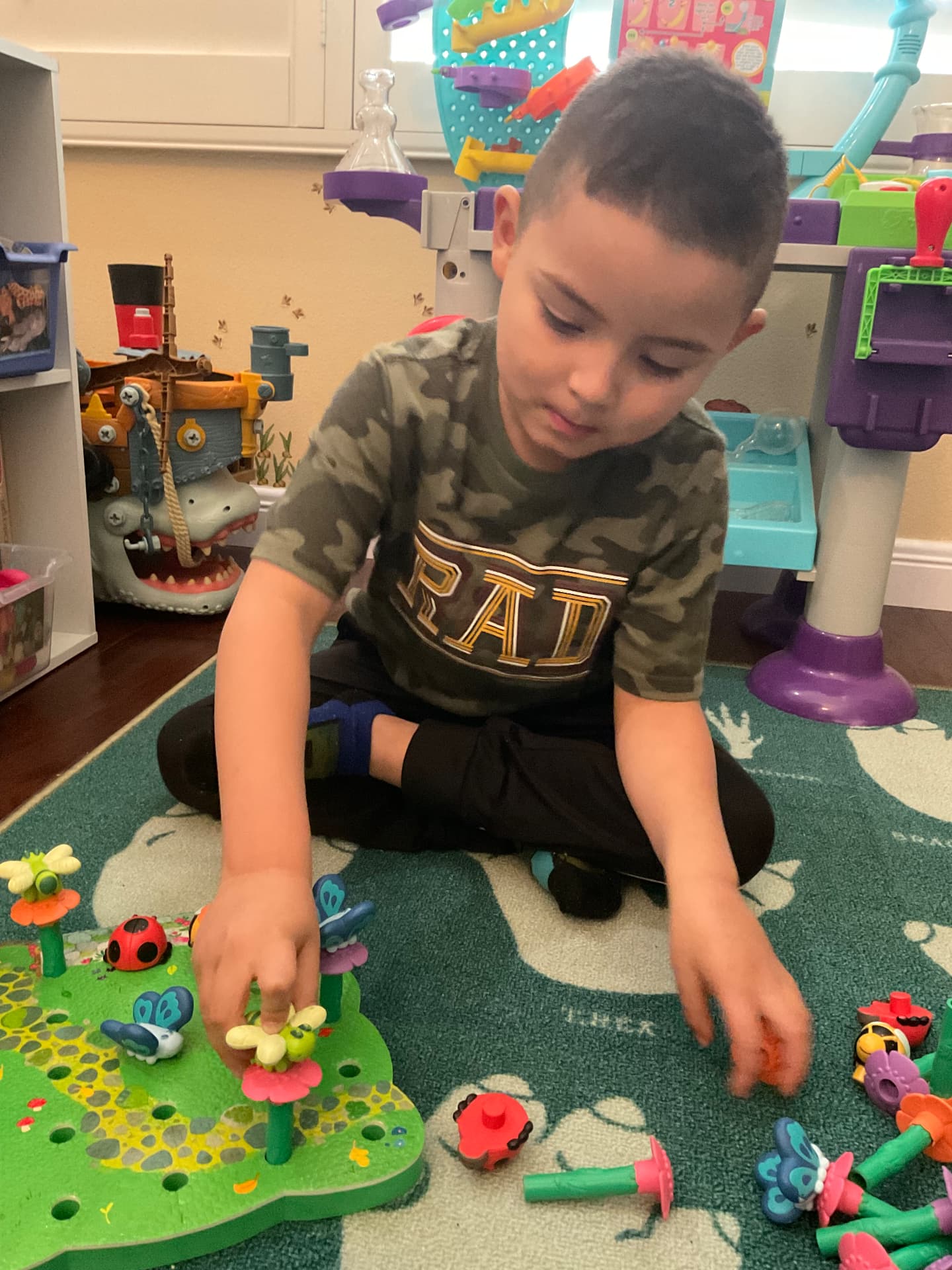 Child arranging flower and bug pegs on a garden board