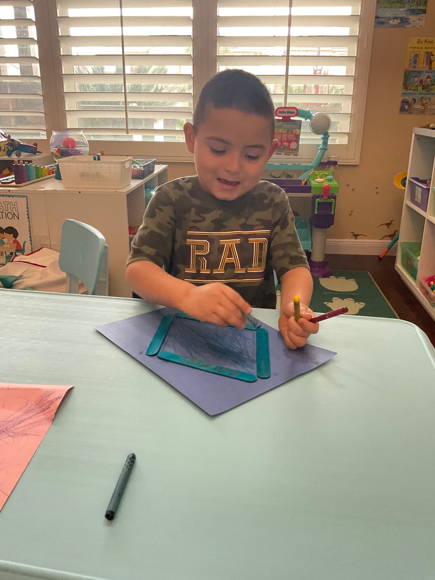 Child making a crayon rubbing on construction paper