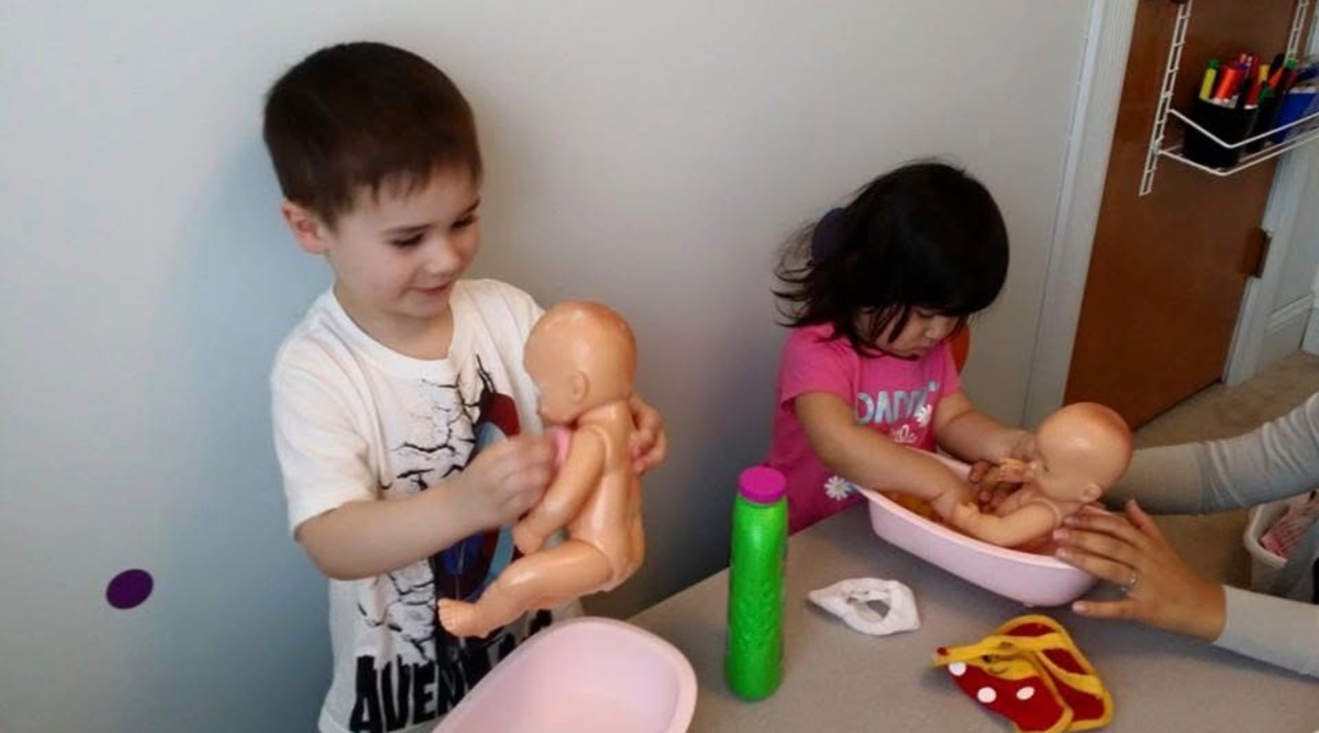 Children washing baby dolls at the table